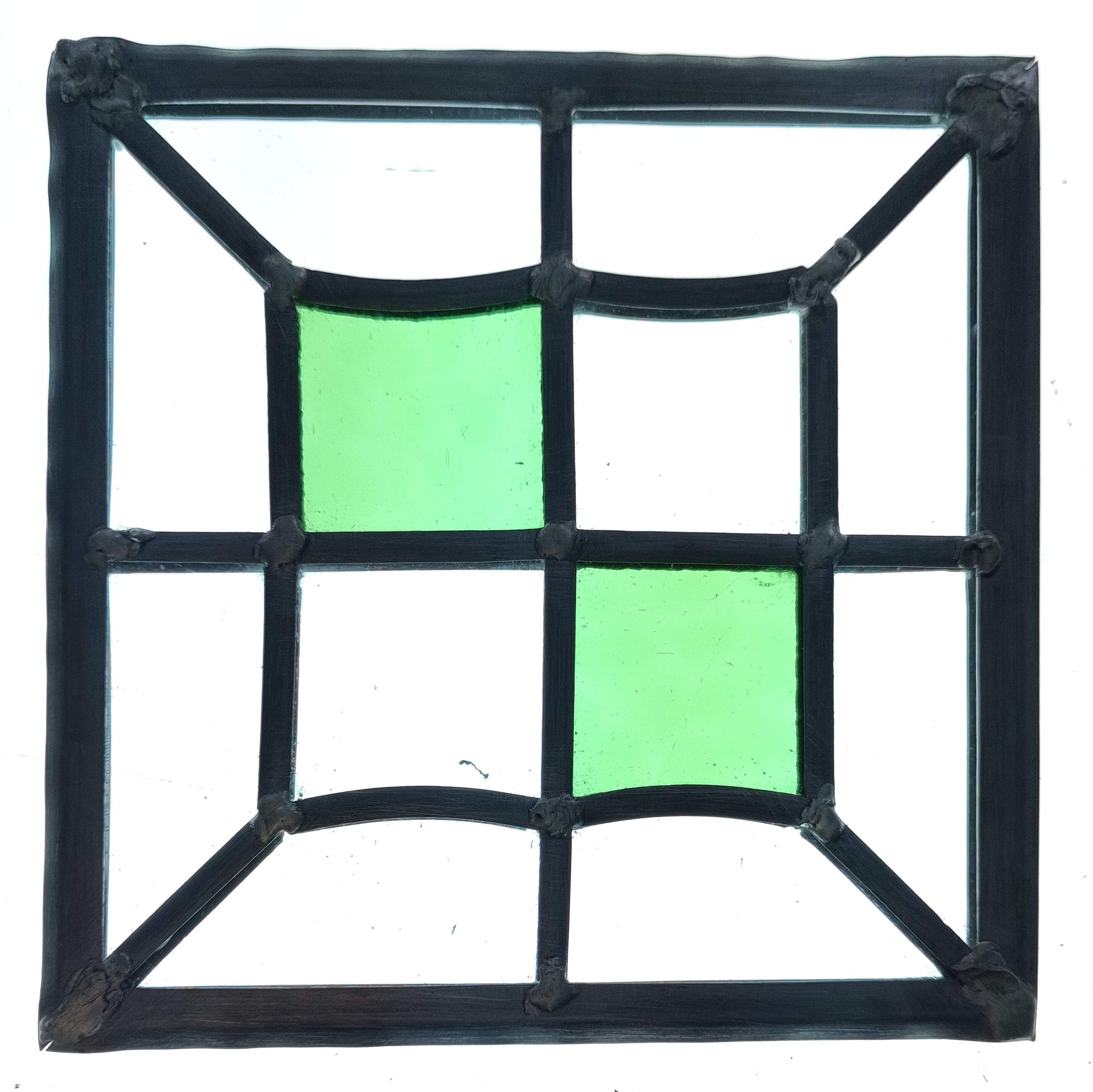 An image of a simple stained glass panel, mostly made of clear, float glass. Two green pieces have been added in the middle, creating a Batternberg effect. The piece is lit up from the back so the light comes through it.